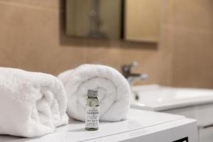 a bottle of alcohol sitting on a bathroom counter with towels at ZenBNB - Évasion - Colocation - Ch 39 - Proche Transport in Annemasse