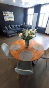 een houten tafel met stoelen en een vaas met bloemen erop bij Brussel-center lux apartment in Brussel