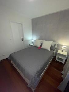 a bedroom with a large bed with two tables and two lamps at Por do Sol in Caniço