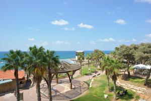 a view of a park with palm trees and the ocean at Residence Beach Hotel in Netanya