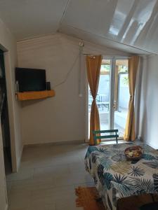 1 dormitorio con 1 cama, TV y ventana en Le cerisier, en Entre-Deux