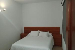 1 dormitorio con 1 cama con sábanas y almohadas blancas en Ca'Xexu en Telde