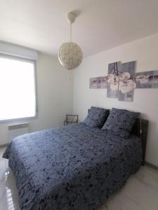 1 dormitorio con cama azul y lámpara colgante en Les Portes du Soleil, en Grabels