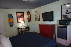 a bedroom with a bed and a flat screen tv at Huntington Surf Inn in Huntington Beach