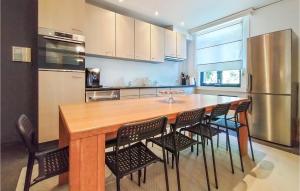 a kitchen with a wooden table with chairs and a refrigerator at De Lindenhoeve in Sint-Katelijne-Waver