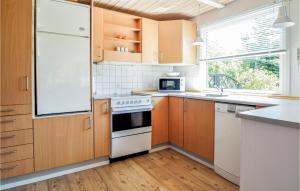 cocina con armarios de madera y nevera blanca en 2 Bedroom Gorgeous Home In Fars en Hvalpsund
