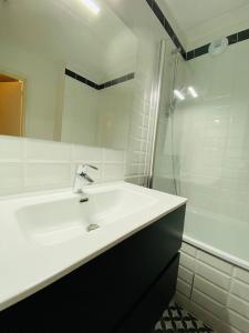 biała łazienka z umywalką i prysznicem w obiekcie Super cozy appartement w mieście Marquette-lès-Lille