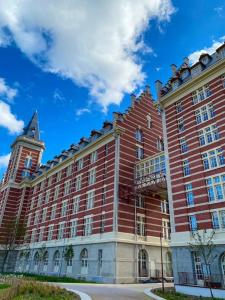 duży czerwony budynek z wieżą na górze w obiekcie Super cozy appartement w mieście Marquette-lès-Lille