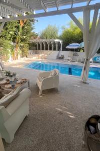 um pátio com uma piscina, cadeiras e uma mesa em Riverland beach villa em Protaras
