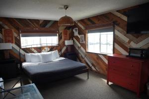 a bedroom with a bed and a dresser and two windows at Huntington Surf Inn in Huntington Beach