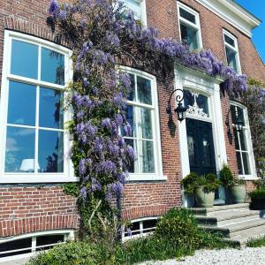 une maison avec des fleurs violettes sur son côté dans l'établissement Ark van Thesinge, 