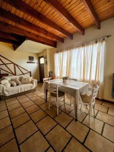 ein Wohnzimmer mit einem Tisch, Stühlen und einem Bett in der Unterkunft Calida cabaña in Ushuaia