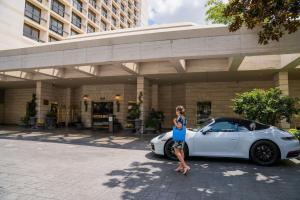 a woman standing next to a white car in front of a building at The St. Regis Houston in Houston