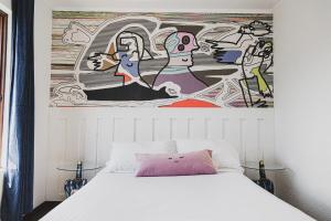 a bedroom with a white bed with a painting on the wall at hotel velero cavancha in Iquique +41 photos
