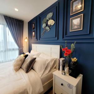 a bedroom with blue walls and a white bed at KnightsBridge BTS Bearing in Ban Khlong Samrong