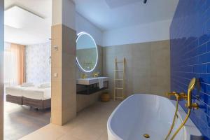 a bathroom with a tub and a sink and a bed at Hotel Stad aan Zee Vlissingen in Vlissingen