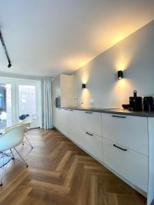 a kitchen with white cabinets and a wooden floor at Studio 157, in de stad aan de gracht in Kampen