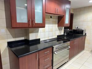 a kitchen with wooden cabinets and a stove top oven at Grand Florida Beach Hostel in Dubai