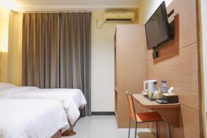 a hotel room with two beds and a desk with a television at City Hotel Mataram in Mataram