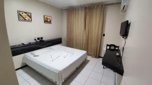 a hotel room with a bed and a television at Pousada Cardoso in Ipiaú