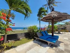 una silla azul bajo una sombrilla junto a la playa en melaya beach resort 2, en Penginuman