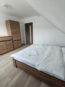 a white bedroom with a bed and a dresser at Casa Alex in Gălăuţaş