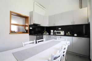 eine weiße Küche mit einem weißen Tisch und Stühlen in der Unterkunft Körtefa Vendégház Keszthely in Keszthely