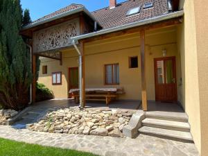 ein Haus mit einer Bank und einer Steinterrasse in der Unterkunft Körtefa Vendégház Keszthely in Keszthely