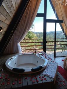 a bath tub in a room with a large window at Chalés Capivari in Campos do Jordão