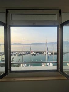- une fenêtre dans une chambre avec vue sur le port de plaisance dans l'établissement Charmant studio - Vue panoramique lac, à Meillerie