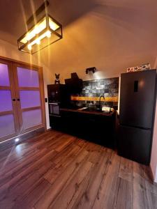 a kitchen with a black refrigerator and a wooden floor at Charmant studio - Vue panoramique lac in Meillerie