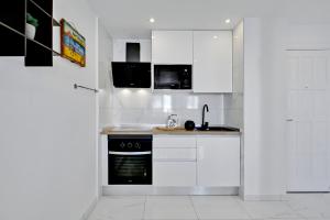 a kitchen with white cabinets and a black oven at Paradise Luxury Apartment in Playa Paraiso