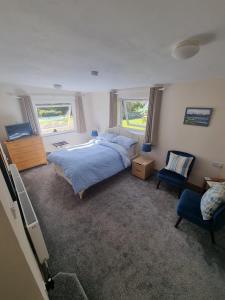 a bedroom with a bed and a chair and two windows at Hillview in Inverness