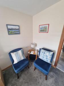 twee blauwe stoelen en een tafel in een kamer bij Hillview in Inverness