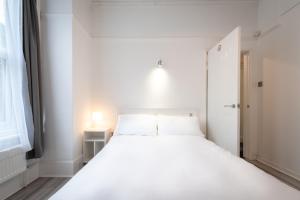 um quarto branco com uma cama branca e uma janela em The Avenue Gem Stylish 2 Bed Stay in the Heart of Southampton em Southampton