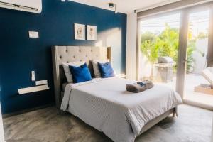 - une chambre avec un grand lit aux murs bleus dans l'établissement PALM VILLAS, à Sainte-Anne