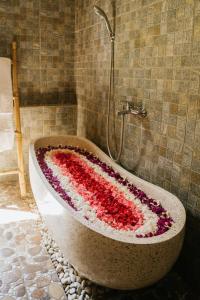 La salle de bains est pourvue d'une baignoire à la décoration florale. dans l'établissement Meng Bengil Villa, à Ubud