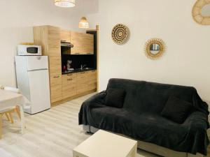 a living room with a black couch and a kitchen at Les Trilles in Valras-Plage
