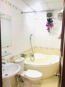 a bathroom with a toilet and a tub and a sink at Huế thương Hotel in Hue