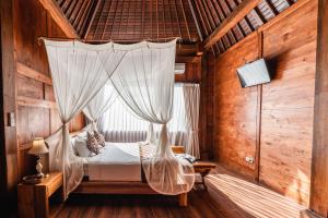 a bedroom with a canopy bed with white curtains at Meng Bengil Villa in Ubud