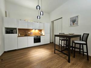 プラハにあるLuxury apartment in the heart of Pragueの白いキャビネット、テーブルと椅子付きのキッチンが備わります。