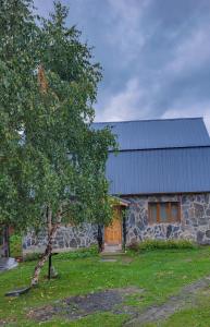 een stenen huis met een boom ervoor bij Guest house Data in Ushguli