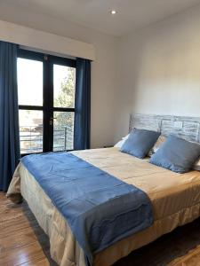 a bedroom with a bed with blue pillows and a window at TOWER Adults only in Villa General Belgrano