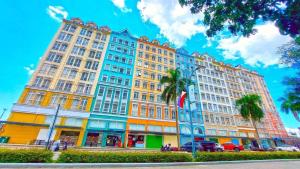 a large building on a street with palm trees at Neat Unit in Holland Park Southwoods in Biñan
