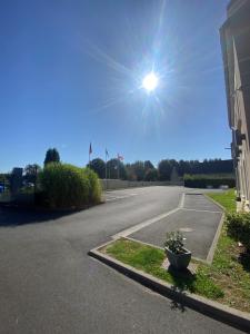 an empty street with the sun in the sky at Hotel Best Western La Mare Ô Poissons in Ouistreham
