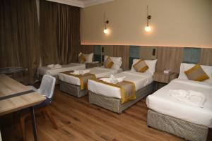a hotel room with three beds and a table at Roya Al Andalus Hotel in Al Madinah