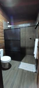 a bathroom with a toilet and a black door at Morooka ÁGUA chalé com hidromassagem ALTER CHÃO in Alter do Chao