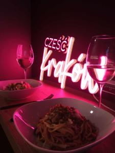 a table with a plate of pasta and a glass of wine at Apartamenty Cześć Kraków in Kraków