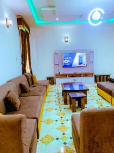Select Elegant 3 Rooms 3 sized king-bed @ Abuja FCT في أبوجا: غرفة معيشة مع كنب وتلفزيون بشاشة مسطحة
