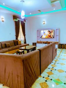 Select Elegant 3 Rooms 3 sized king-bed @ Abuja FCT في أبوجا: غرفة معيشة مع كنب وتلفزيون بشاشة مسطحة